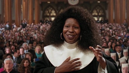 Whoopi Goldberg conducts a choir wearing a nun's habit but no wimple.