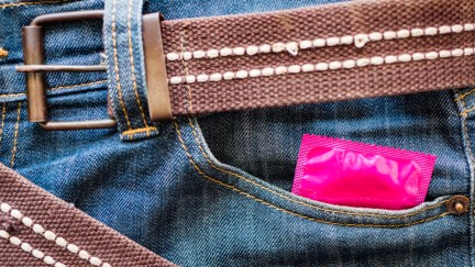 A pink condom wrapper peek out of a jeans pocket