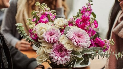 Man holding a bouquet of flowers talking to women.