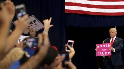 Donald Trump holds a Women for Trump sign at a campaign rally