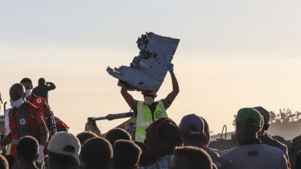 TOPSHOT - A man carries a piece of debris on his head at the crash site of a Nairobi-bound Ethiopian Airlines flight near Bishoftu, a town some 60 kilometres southeast of Addis Ababa, Ethiopia, on March 10, 2019. - A Nairobi-bound Ethiopian Airlines Boeing crashed minutes after takeoff from Addis Ababa on March 10, killing all eight crew and 149 passengers on board, including tourists, business travellers, and 