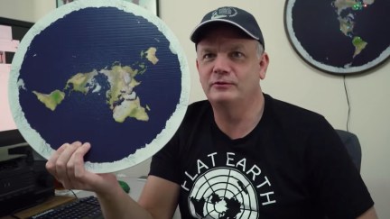 mark sargent holding up a round image of a flat Earth in behind the curve