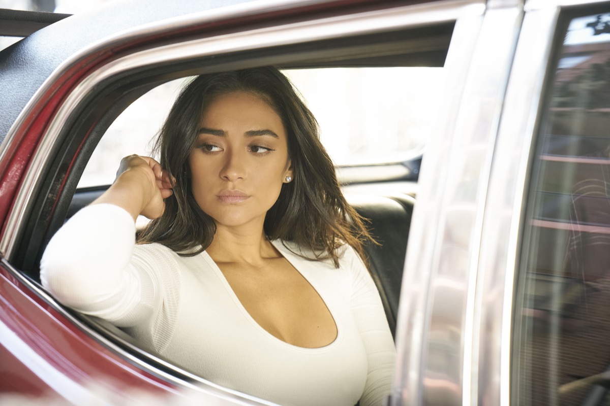 Shay Mitchell as Peach Salinger sitting in a car in Netflix's You.