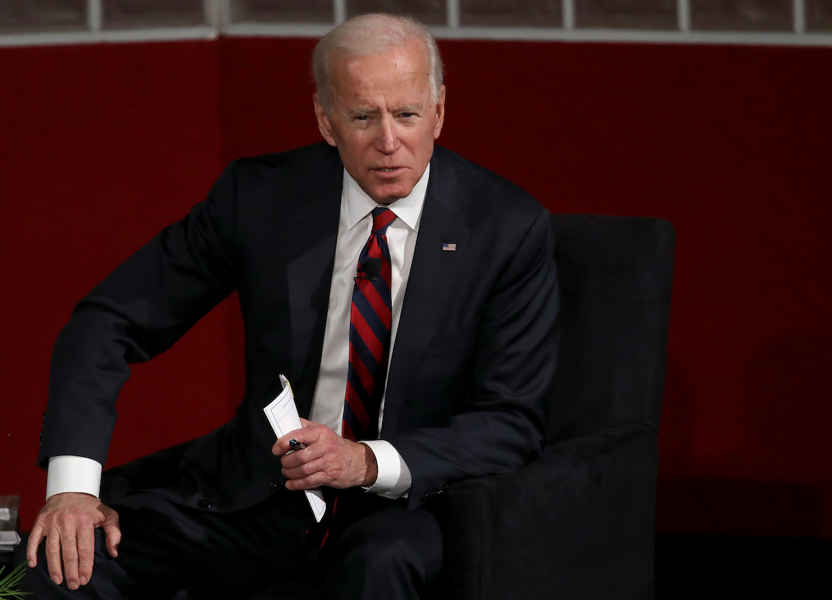 Joe Biden seated, leaning forward and speaking.