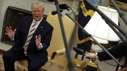 Donald Trump rants in the Oval Office, surrounded by reporters' microphones.