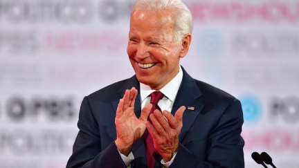 Joe Biden laughs and claps on the debate stage.