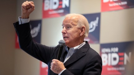 Joe Biden holds a microphone and raises a fist at an Iowa event.