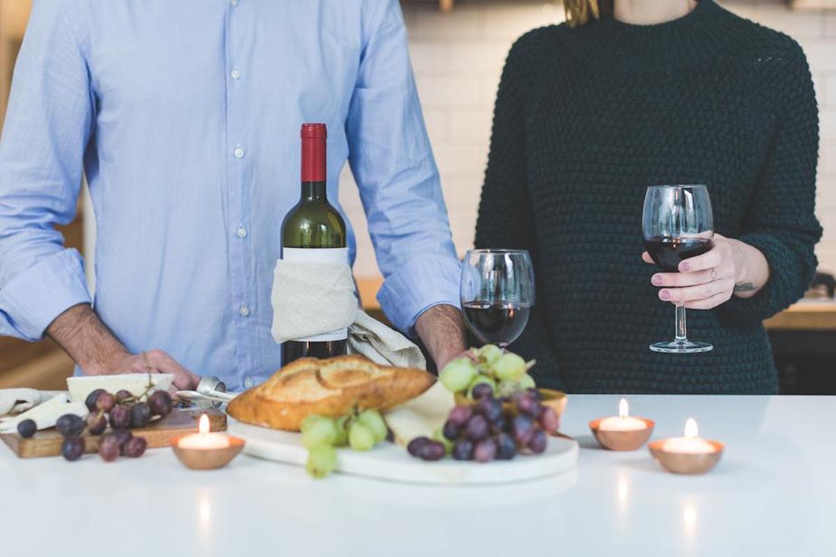 Heterosexual couple with wine and a cheese plate in front of them.