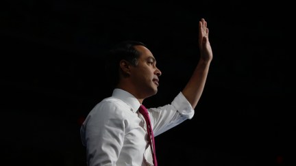 Julian Castro waves in profile in front of a black background.