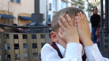 A young boy bruies his face in his hands.