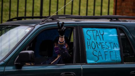 A protestor shows a sign while driving past the Governor's Mansion during a drive by protest in Atlanta, Georgia