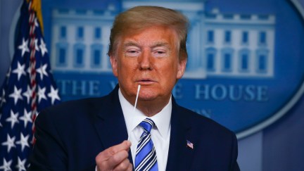 Donald Trump holds up swabs as he speaks at the daily coronavirus briefing at the White House