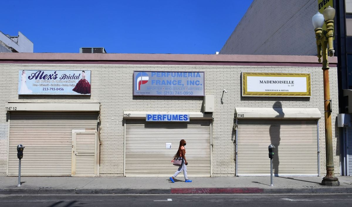 A woman walks past closed shopfronts in what would be a normally busy fashion district in Los Angeles, California on May 4, 2020. - California governor Gavin Newsom earlier today announced the gradual reopening of the state later this week as dismal US employment figures are expected with the release of figures Friday May 8 for April's US jobs report, as 30 million Americans filed for unemployment in the last six weeks. (Photo by Frederic J. BROWN / AFP) (Photo by FREDERIC J. BROWN/AFP via Getty Images)