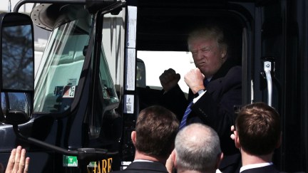 Trump pretends to drive a big boy truck.