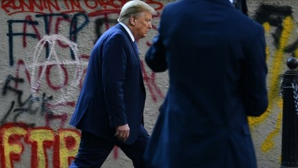 Donald Trump walks past graffiti back to the White House escorted by the Secret Service