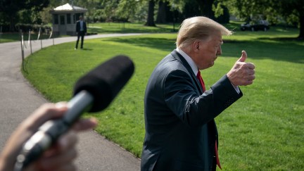 Donald Trump frowns and gives a thumbs up to a reporter.