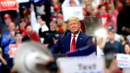 Donald Trump smirks from the podium during a campaign rally.