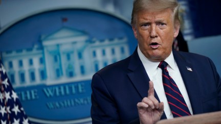 Donald Trump holds his index finger up at reporters during a press briefing.