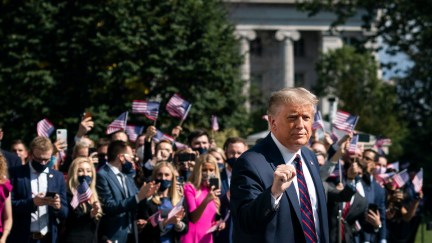 Donald Trump gestures as White House interns cheer him on as he leaves the White House residence