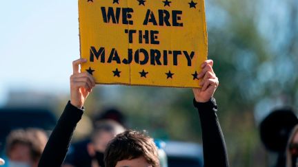 A protester holds a sign reading 'we are the majority.'