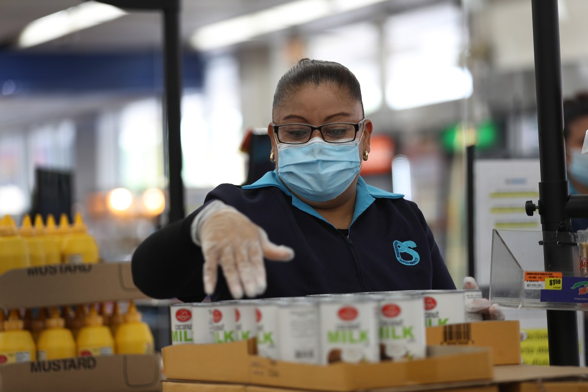 MIAMI, FLORIDA - APRIL 13: Lorena Martinez wears a mask and gloves as she works as a cashier at the Presidente Supermarket on April 13, 2020 in Miami, Florida. The employees at Presidente Supermarket, like the rest of America's grocery store workers, are on the front lines of the coronavirus pandemic, helping to keep the nation's residents fed. (Photo by Joe Raedle/Getty Images)