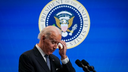 Joe Biden scratches his head in front of the presidential seal.