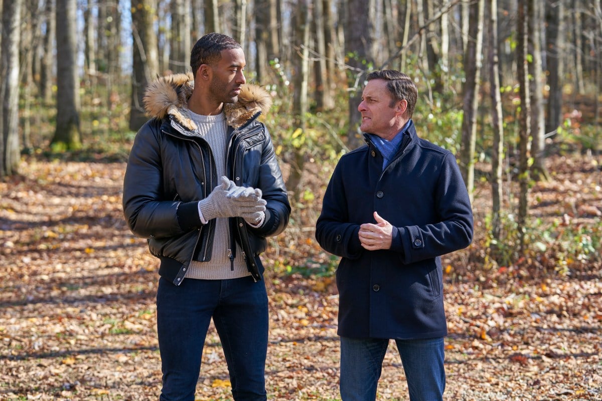 Chris Harrison and Bachelor Matt James stand in the woods, looking at each other.