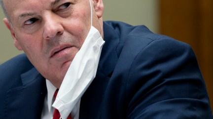 United States Postal Service Postmaster General Louis DeJoy looks angry with a mask hanging from his ear while testifying during a House Oversight and Reform Committee hearing