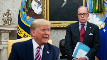 National Economic Council Director Larry Kudlow (R) looks on as then-president Donald Trump speaks to reporters in the Oval Office of the White House