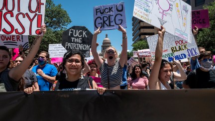 Protesters hold up signs as they march down Congress Ave at a pro-abortion protest