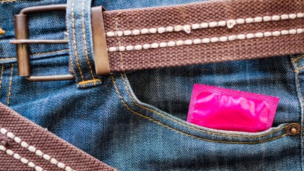 A pink condom wrapper peek out of a jeans pocket