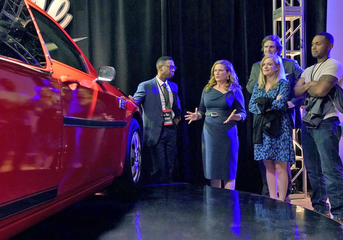 The cast of American Auto looking at a car