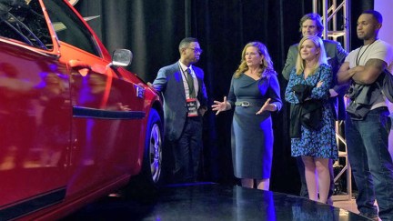 The cast of American Auto looking at a car