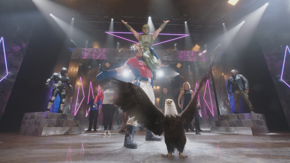 The cast of Peacemaker poses at the end of a dance number, with Eagly the eagle in front, wings outspread