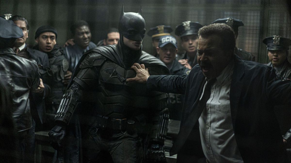 Lieutenant Jim Gordon (Jeffrey Wright) holding back Batman (Robert Pattinson) and several police officers in the Gotham police department.