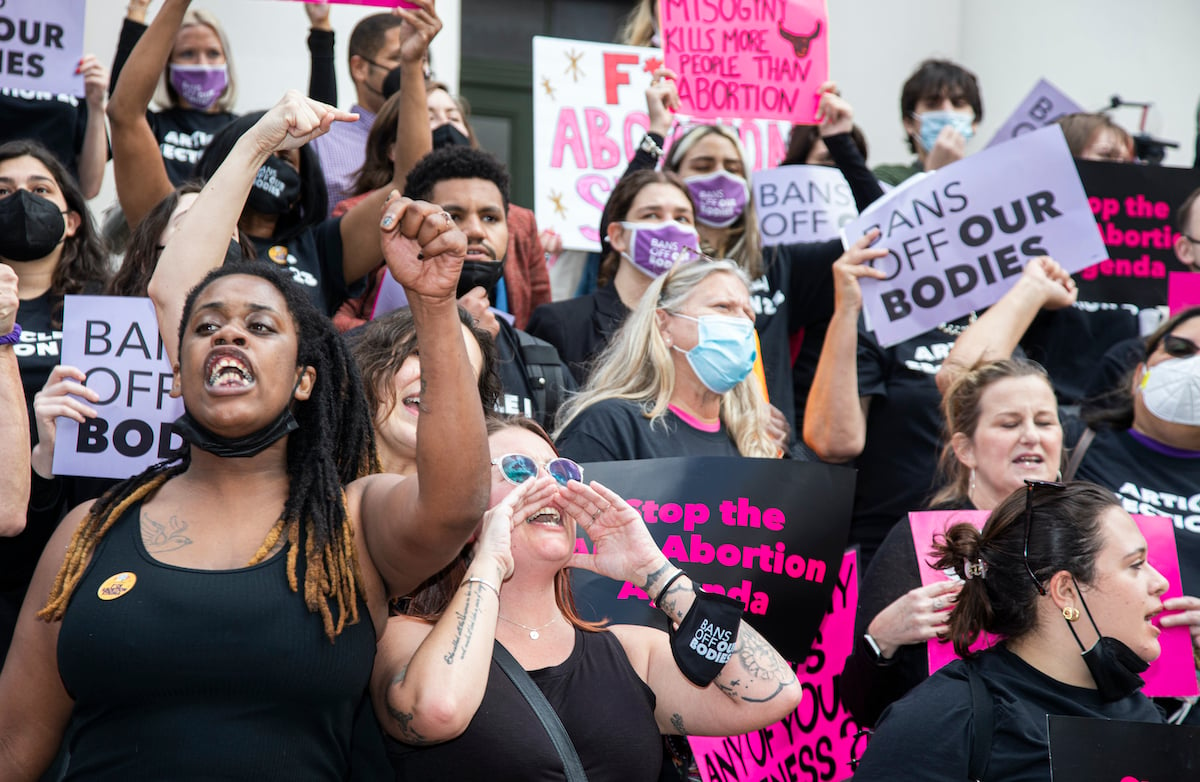 A group of protesters rally for abortion rights with raised fists and signs.