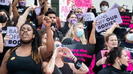 A group of protesters rally for abortion rights with raised fists and signs.