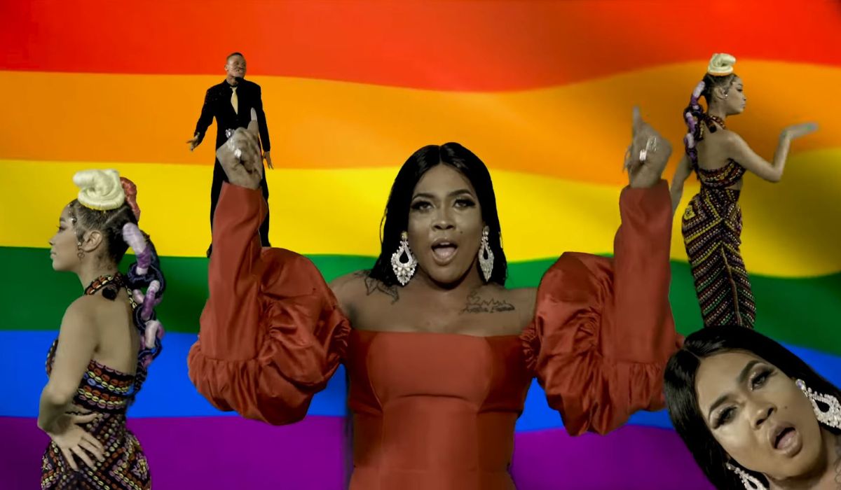 Angel Maxine singing her song Wo Fi in front of a large LGBTQ+ flag. Image: screencap.