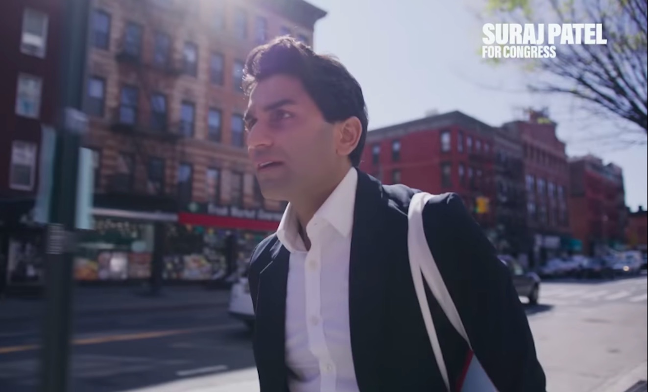 A man in a dress shirt and jacket walks down a city street.