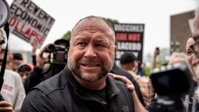 Alex Jones grimaces, surrounded by protestors