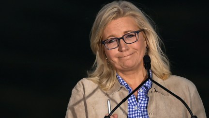 Liz Cheney gives an unhappy, tight-lipped smile from a podium during her concession speech.