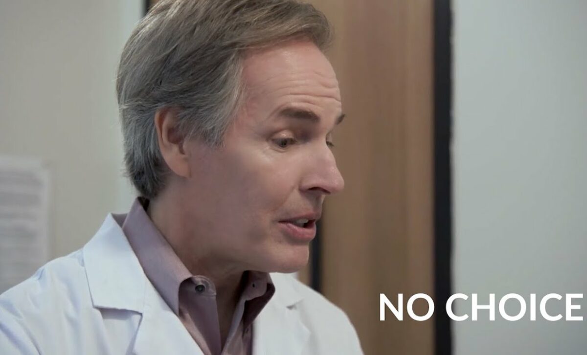 A white man in a white doctor's coat talks with the words "no choice" on screen next to him