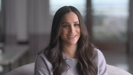 Meghan Markle sits on a couch and smiles in 'Harry & Meghan.'