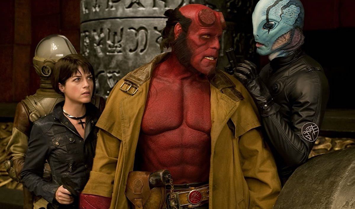 Hellboy (Ron Perlman), Liz (Selma Blair), Abe Sapien (Doug Jones), and Johann Kraus (John Alexander and James Dodd) stand against a golden wall in 'Hellboy II: The Golden Army'