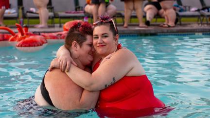 Two fat women embrace in a swimming pool