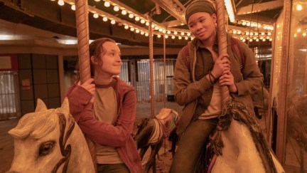 Ellie and Riley sit on merry go round horses, smiling at each other.