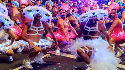 A group of drag performers dance in the street during a Pride parade.