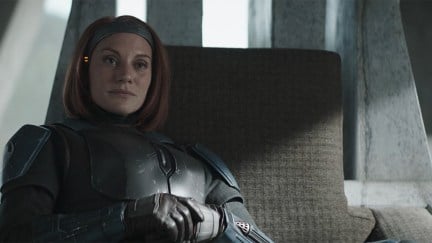 Bo-Katan Kryze (Katee Sackhoff) sitting on her throne in her castle talking to din on the mandalorian