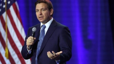 Ron Desantis speaks into a microphone at an event.