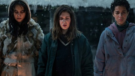 Lottie, Shauna, and Taissa stand in the snow, looking troubled, in Yellowjackets.